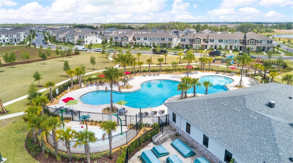 An aerial view shows a community swimming pool and splash pad next to a clubhouse — 15767 WATER SPRING BOULEVARD, WINTER GARDEN, FL