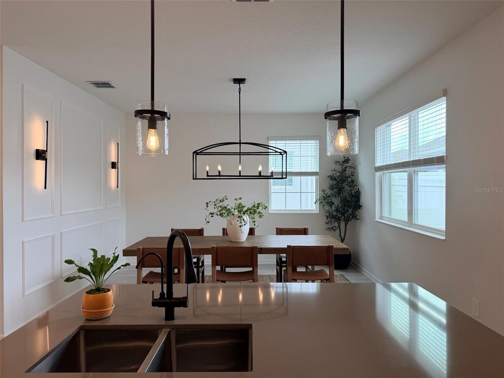 A dining area with a wooden table, leather chairs, and modern black light fixtures — 15767 WATER SPRING BOULEVARD, WINTER GARDEN, FL