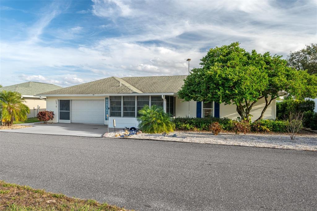 A single-story house with a garage, screened-in porch, and a large tree in the front — 7040 TAMARIND DRIVE, LAKE WALES, FL