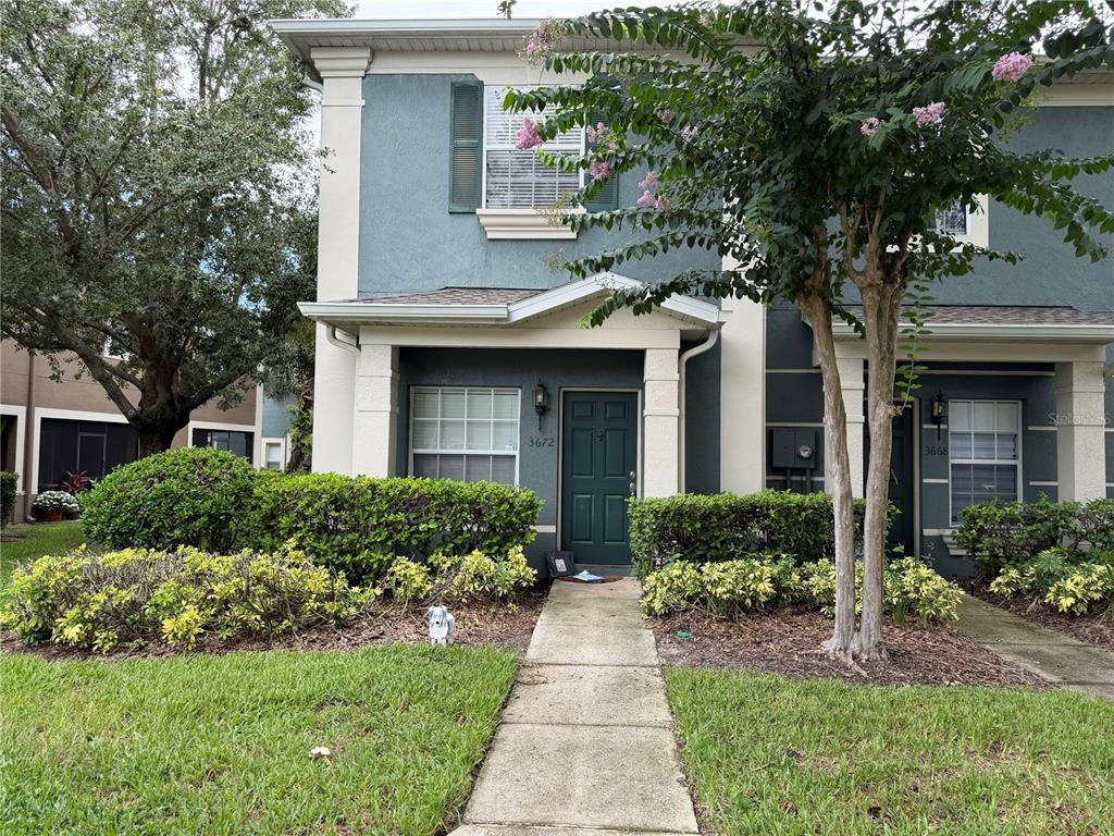 A two-story townhouse exterior features a dark green front door and a concrete walkway — 3672 WILSHIRE WAY ROAD UNIT 263, ORLANDO, FL