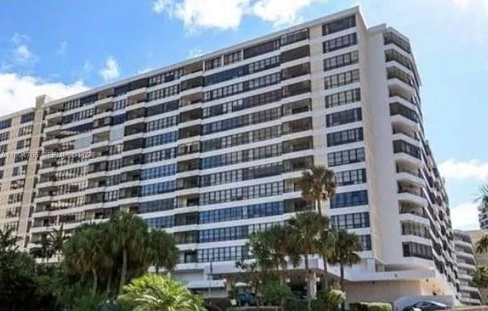 A tall, multi-story residential apartment building with balconies and palm trees in the foreground — 500 Three Islands Blvd # 314, Hallandale Beach FL 33009, HALLANDALE BEACH, FL