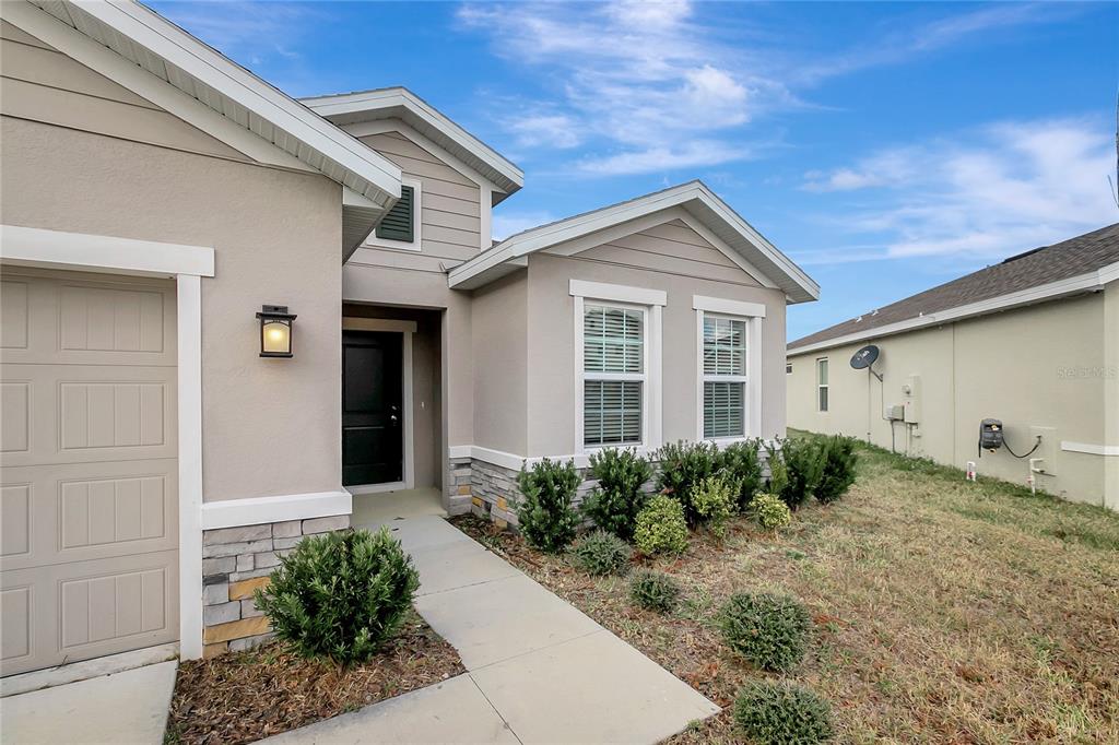 A beige single-story house with a stone veneer base, a garage, and a front walkway — 10209 AGAVE COURT, LAND O LAKES, FL