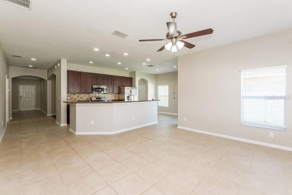 An open-concept kitchen with dark cabinets and a breakfast bar overlooks a tiled living area — 1807 BONITA BLUFF COURT, RUSKIN, FL