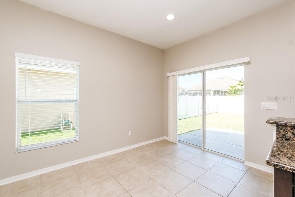 A dining area with tile flooring, beige walls, a window, and sliding glass patio doors — 1807 BONITA BLUFF COURT, RUSKIN, FL