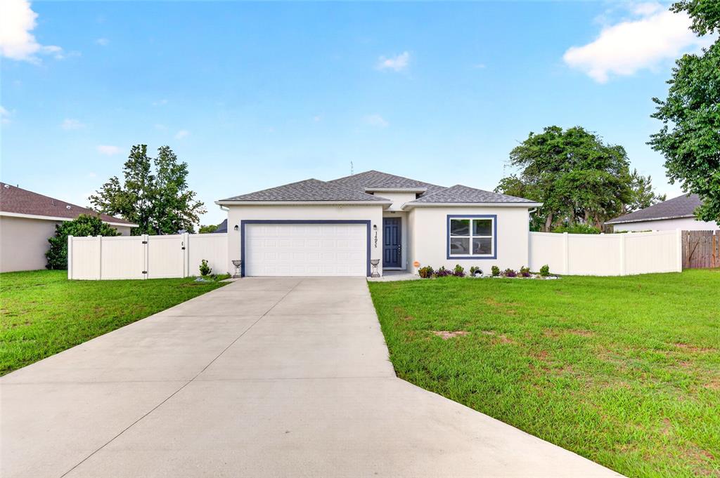 A single-story house with a white exterior, a two-car garage, and a concrete driveway — 14055 SW 30TH TERRACE ROAD, OCALA, FL