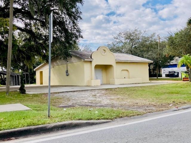 A yellow, single-story building with a stucco exterior and a covered arched entrance — 106 E BERESFORD AVENUE, DELAND, FL