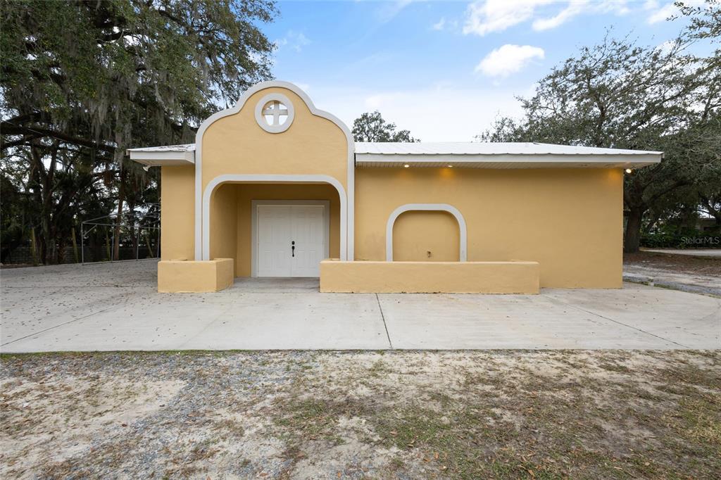 The exterior of a yellow, single-story building features a recessed double-door entrance and a decorative arch — 106 E BERESFORD AVENUE, DELAND, FL