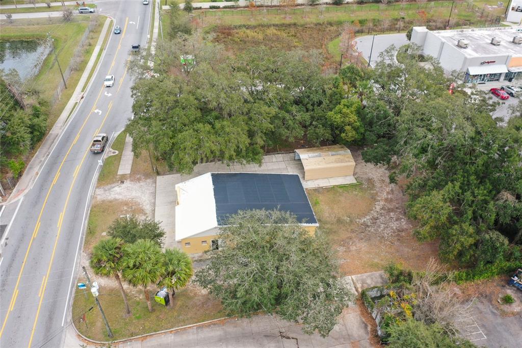 An aerial view shows a commercial building with a solar-paneled roof and a detached carport — 106 E BERESFORD AVENUE, DELAND, FL