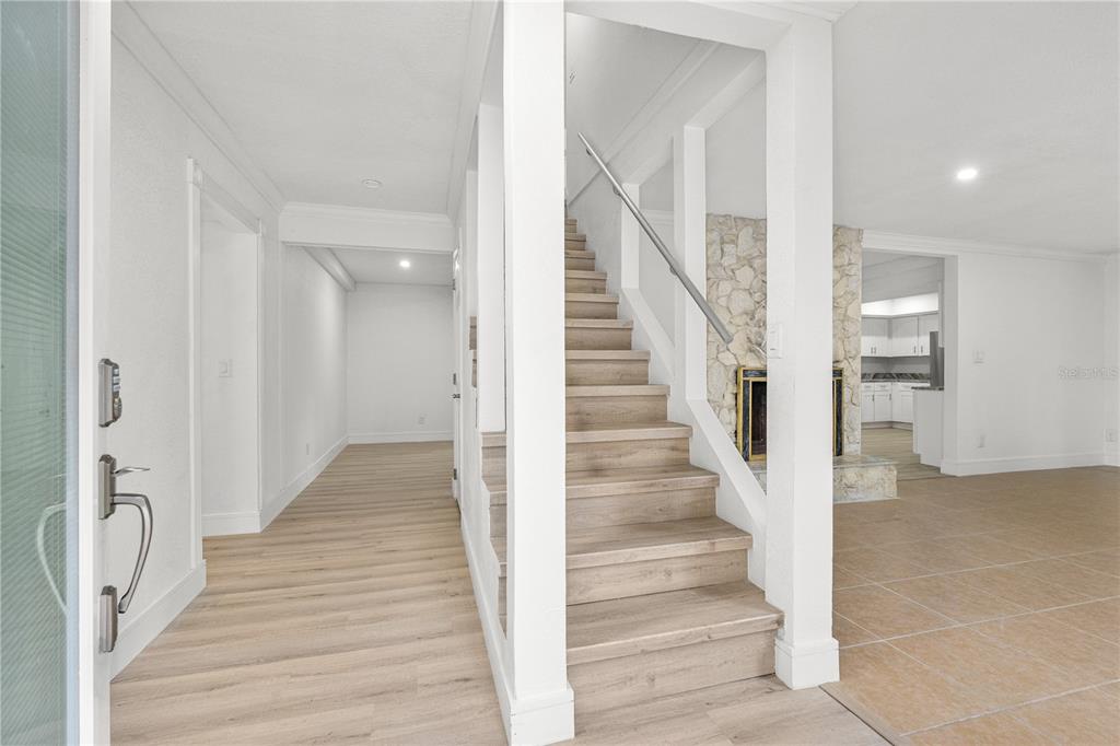 A bright entryway features light wood flooring, a staircase with a metal railing, and tile — 475 E WISCONSIN AVENUE, ORANGE CITY, FL