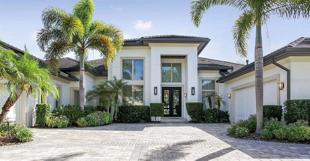 A modern house exterior features a paved driveway, palm trees, and a dark front door — 10372 KENSINGTON SHORE DRIVE, ORLANDO, FL