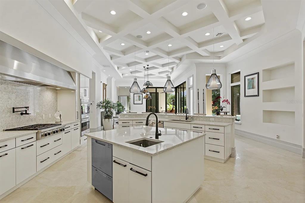 A modern white kitchen features a large center island, coffered ceilings, and stainless steel appliances — 10372 KENSINGTON SHORE DRIVE, ORLANDO, FL