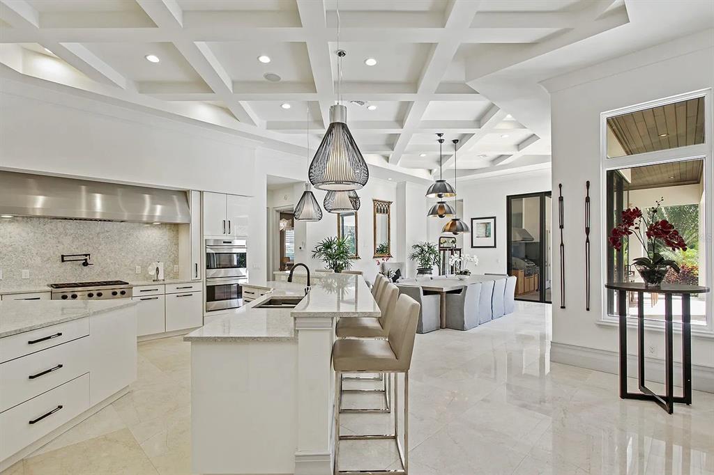 A modern white kitchen features a coffered ceiling, marble floors, and a large center island — 10372 KENSINGTON SHORE DRIVE, ORLANDO, FL