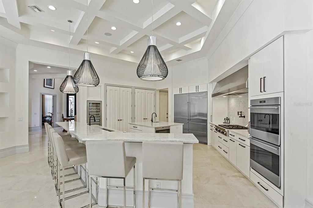 A modern white kitchen features a large island, pendant lighting, and stainless steel appliances — 10372 KENSINGTON SHORE DRIVE, ORLANDO, FL