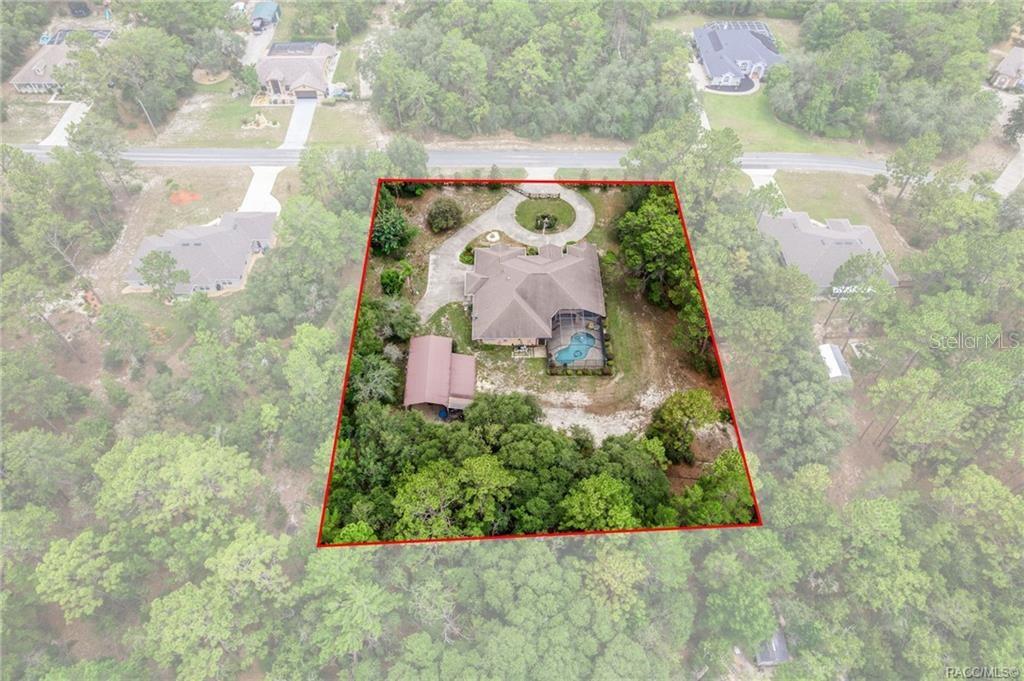 An aerial view shows a house with a pool and detached garage on a wooded lot — 4847 W GEYSER COURT, BEVERLY HILLS, FL