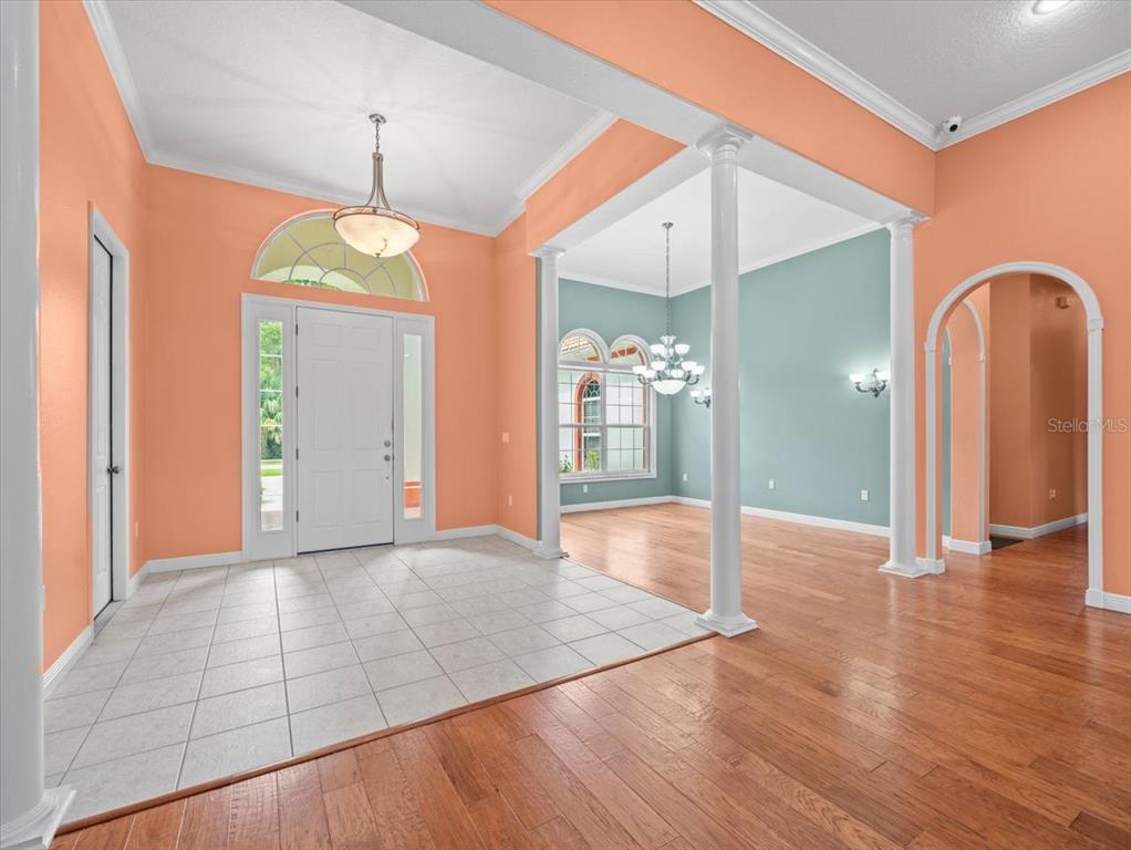 An entryway with tile flooring transitions into a living area with hardwood floors and columns — 8698 MISSISSIPPI RUN, WEEKI WACHEE, FL