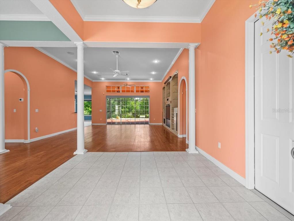 A tiled entryway leads into a living room with hardwood floors and peach-colored walls — 8698 MISSISSIPPI RUN, WEEKI WACHEE, FL
