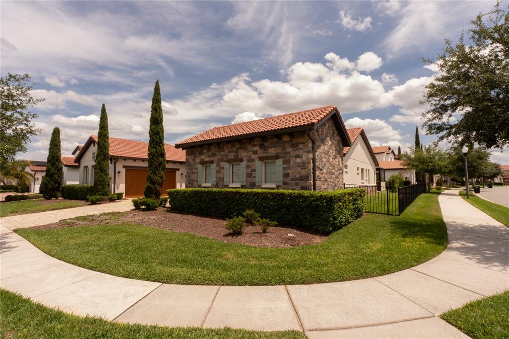 A stone-faced house with a red tile roof sits on a corner lot with landscaping — 15686 PANTHER LAKE DRIVE, WINTER GARDEN, FL