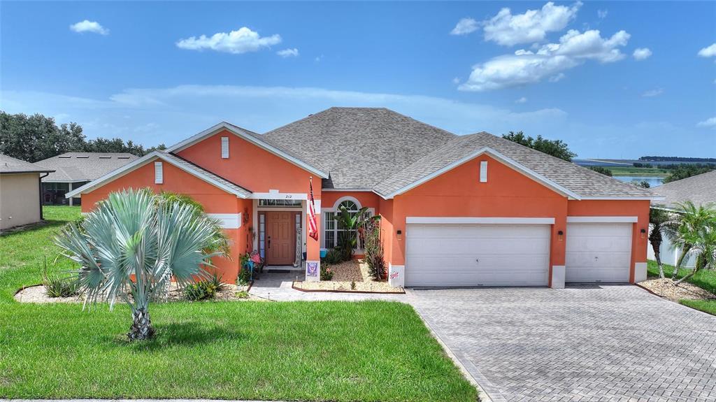 A single-story orange house with a three-car garage and a paved driveway — 212 BROOKSHIRE DRIVE, LAKE WALES, FL