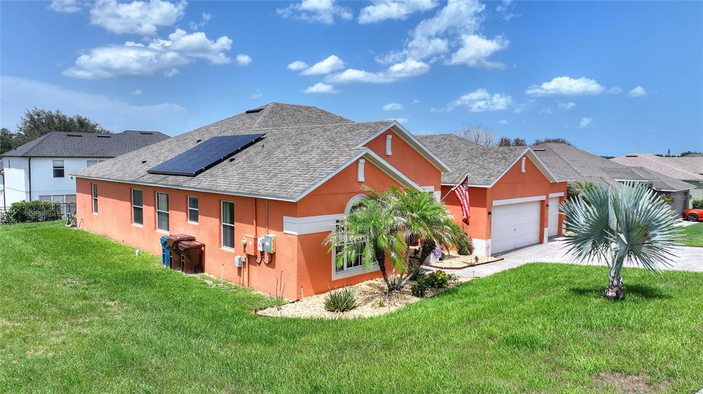 An orange house with a shingled roof, solar panels, and a two-car garage — 212 BROOKSHIRE DRIVE, LAKE WALES, FL