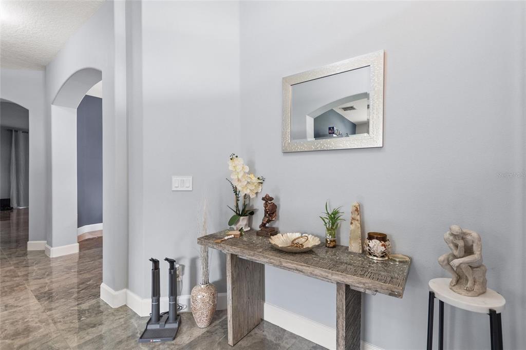 A foyer features a console table, a wall mirror, and a statue on a side stand — 212 BROOKSHIRE DRIVE, LAKE WALES, FL