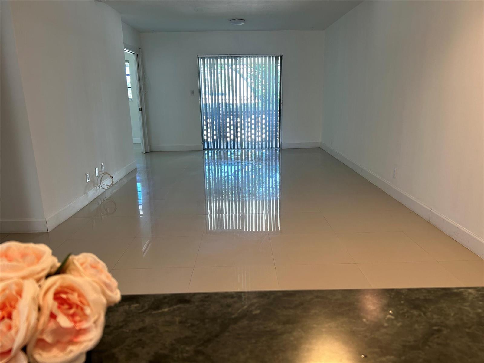 An empty living room features glossy light-colored tile floors and a sliding glass door — 2800 NE 14th St Causeway # 207, Pompano Beach FL 33062, POMPANO BEACH, FL