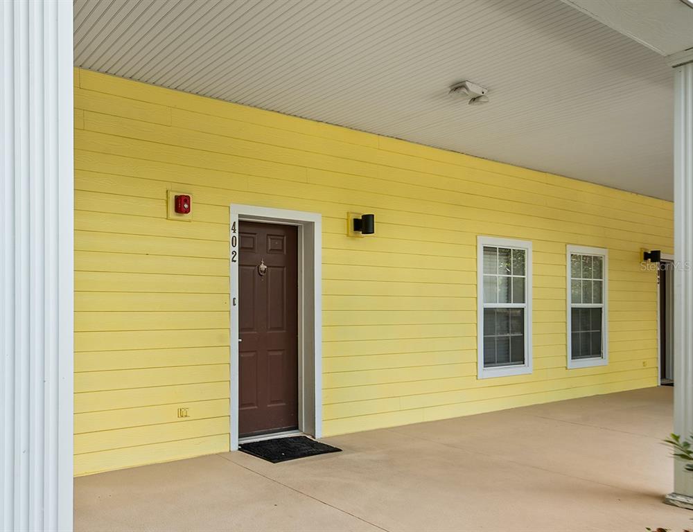 A yellow-sided building exterior features a brown front door labeled 402 and two windows — 402 LUCAYA LOOP, DAVENPORT, FL