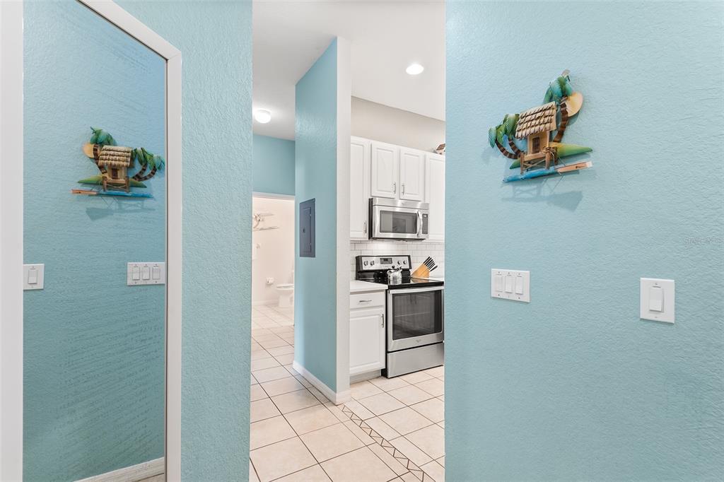 A view through a doorway showing a kitchen with white cabinets and tiled floors — 402 LUCAYA LOOP, DAVENPORT, FL