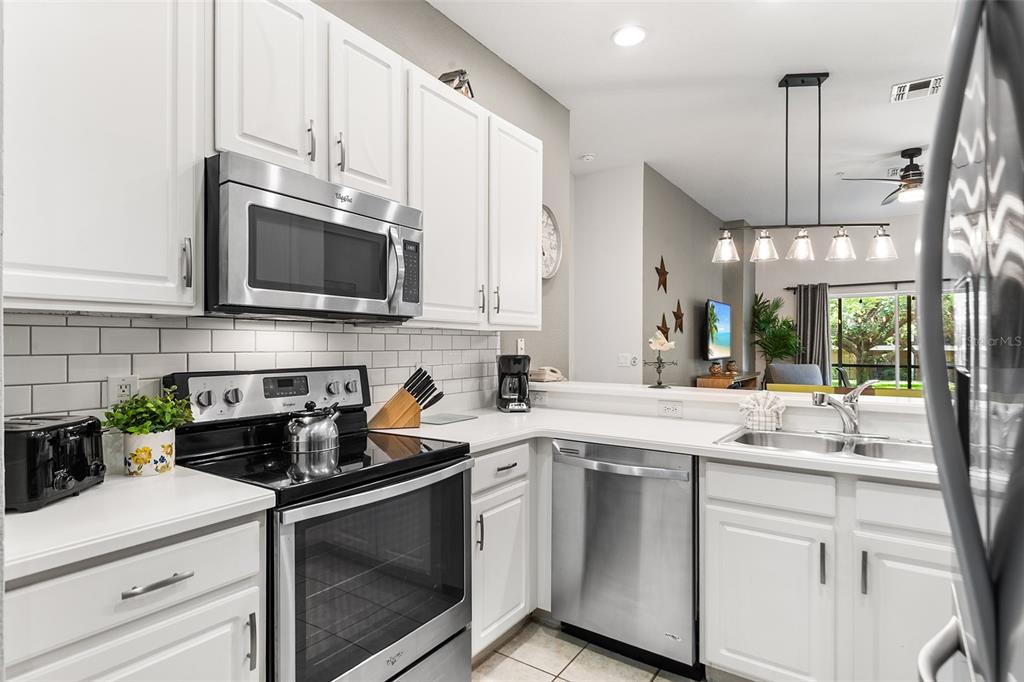 A kitchen with white cabinets, stainless steel appliances, and a subway tile backsplash — 402 LUCAYA LOOP, DAVENPORT, FL