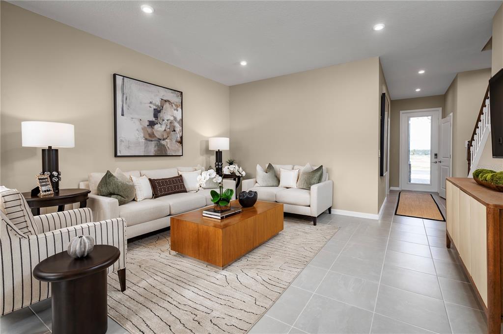 A living room features light-colored sofas, a wooden coffee table, and tile flooring — 12522 AMBER CREEK CIRCLE, LAKEWOOD RANCH, FL