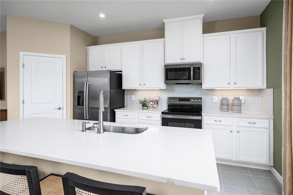 A modern kitchen features white cabinets, a large island with a sink, and stainless appliances — 12522 AMBER CREEK CIRCLE, LAKEWOOD RANCH, FL