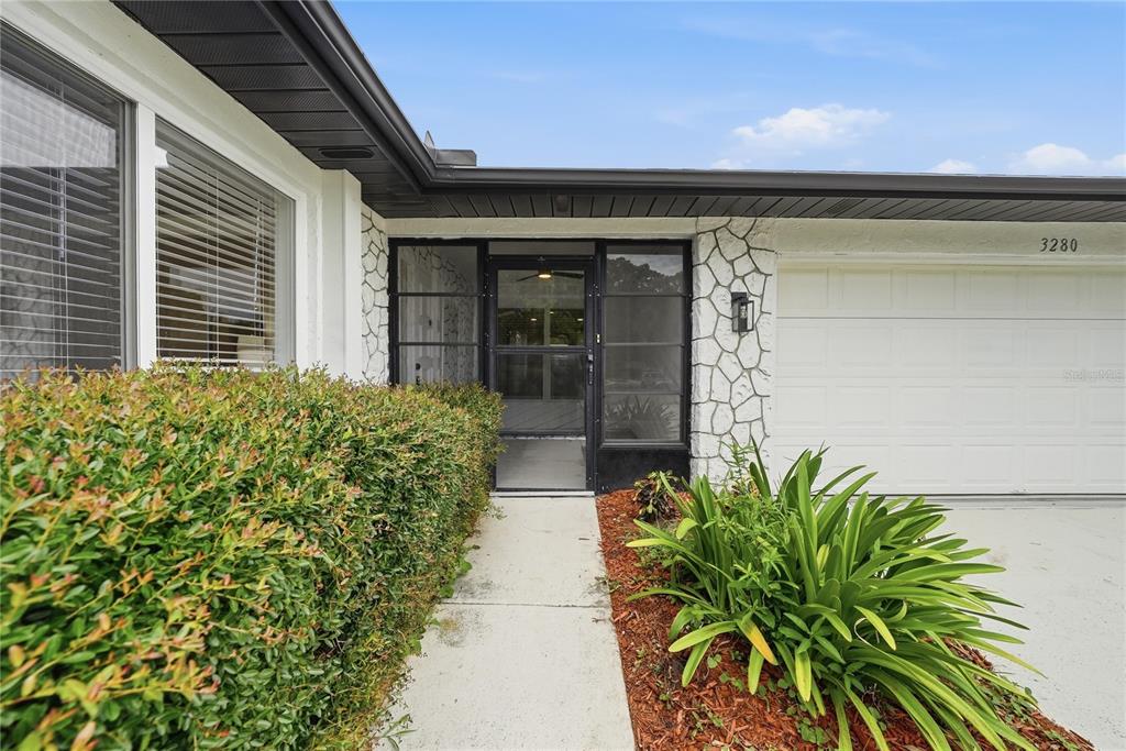 The exterior of a house features a stone-accented wall, a front door, and a garage — 3280 SKENE TERRACE, PALM HARBOR, FL