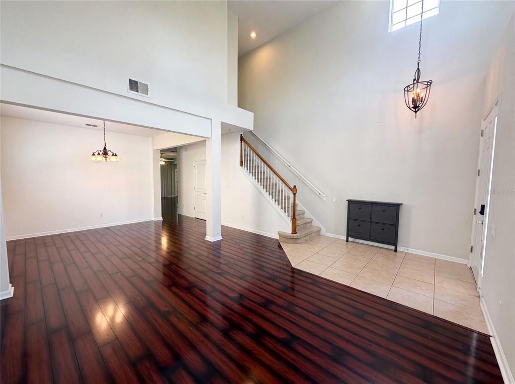 An entryway with tile flooring, a staircase, and a dining area with dark wood floors — 13228 ROSKIN LANE, WINDERMERE, FL