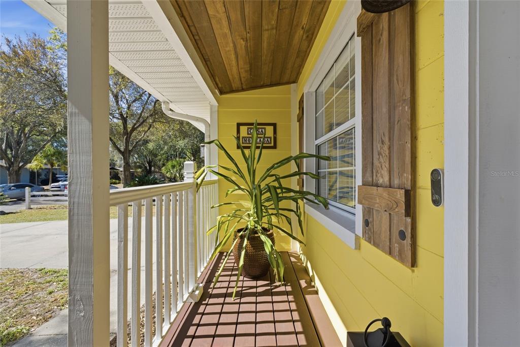 A yellow house porch features a wooden ceiling, a potted plant, and white railings — 1927 ELAND AVENUE, WINTER PARK, FL