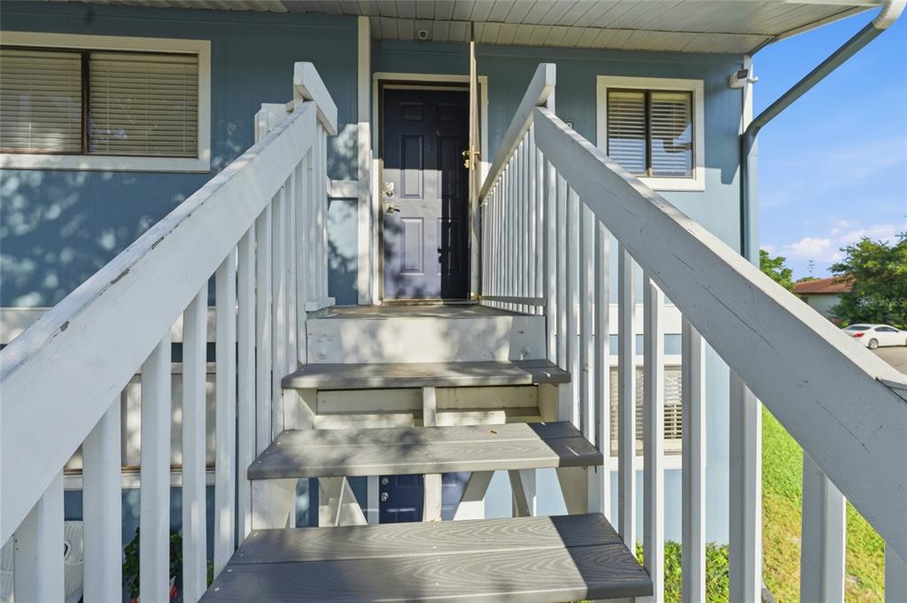 A set of wooden stairs with white railings leads up to an elevated front door — 6033 34TH STREET W UNIT 80, BRADENTON, FL