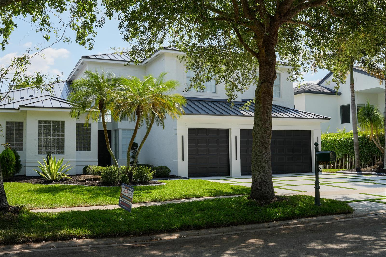 A two-story white house with a dark metal roof, two garage doors, and palm trees — 5227 SW 195th Terrace, Miramar FL 33029, MIRAMAR, FL