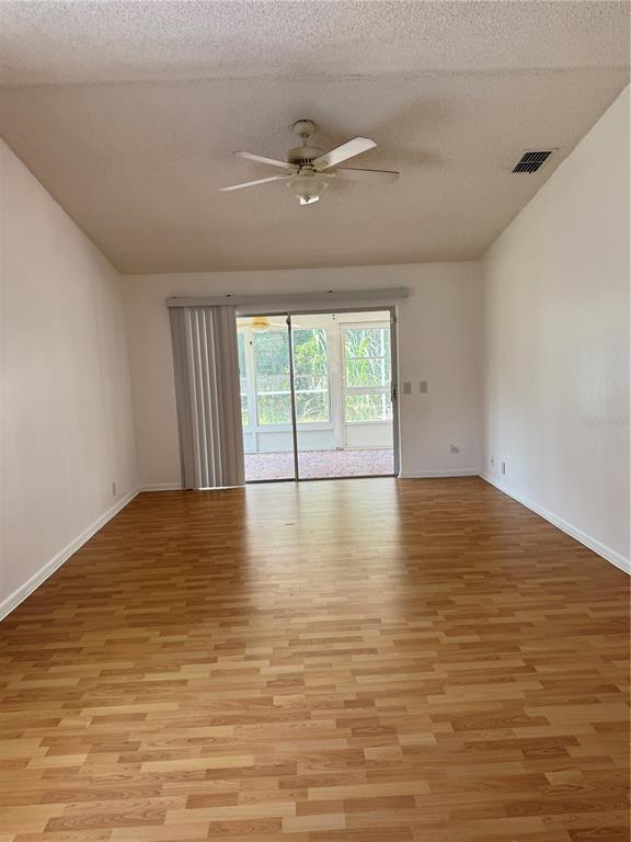 An empty room with wood-look flooring, a ceiling fan, and sliding glass doors to a lanai — 427 GREENFIELD ROAD, WINTER HAVEN, FL