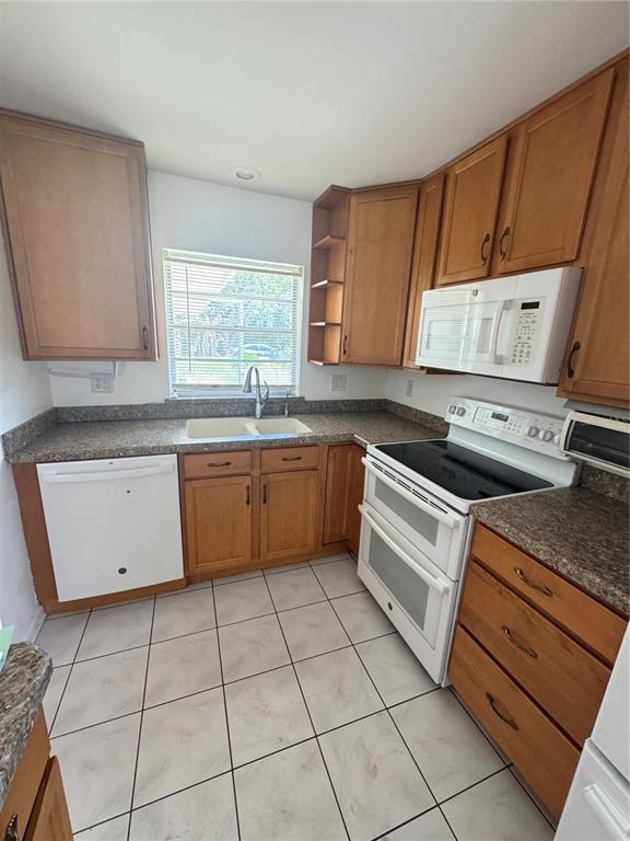 A kitchen features wood cabinets, white appliances, a double sink, and tiled flooring — 427 GREENFIELD ROAD, WINTER HAVEN, FL