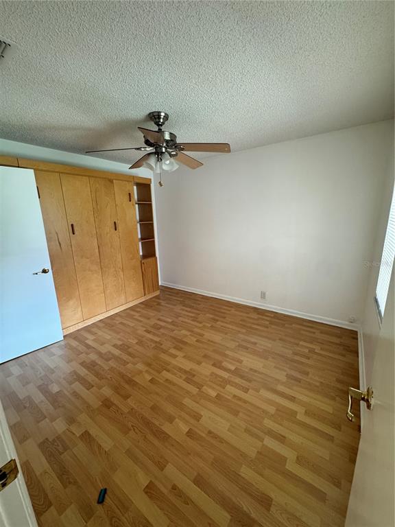 An empty bedroom features wood-look laminate flooring, a ceiling fan, and a built-in wall unit — 427 GREENFIELD ROAD, WINTER HAVEN, FL
