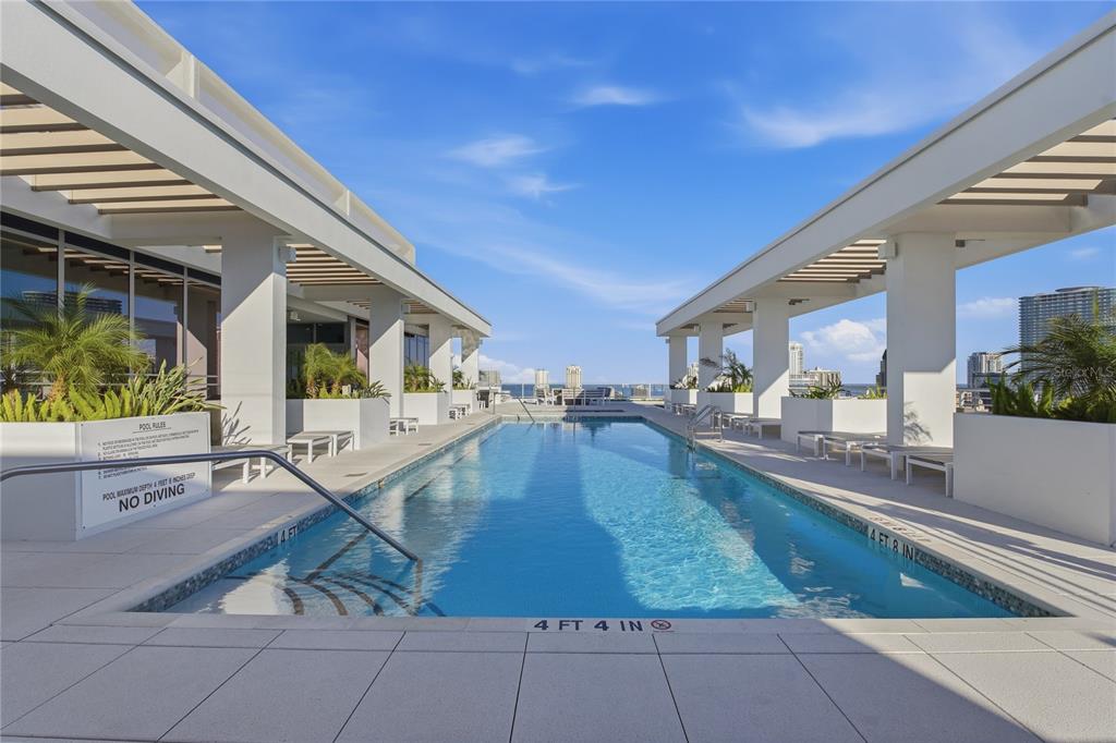 A rectangular swimming pool sits between two covered walkways with lounge chairs on a rooftop — 777 3RD AVENUE N UNIT 1202, ST PETERSBURG, FL