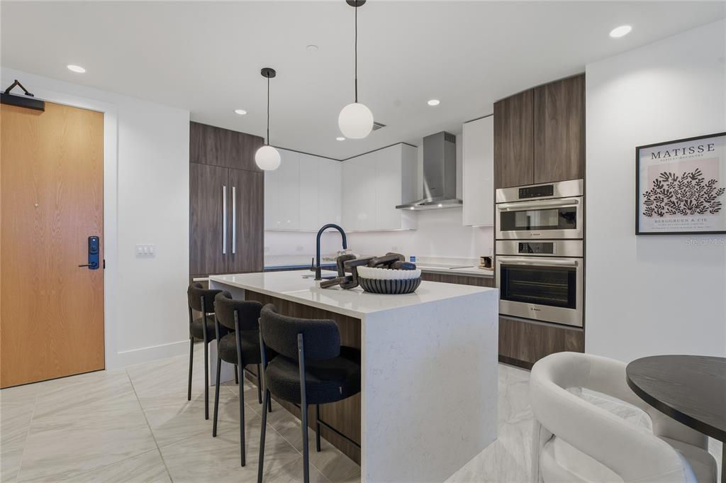 A modern kitchen features a white quartz island, dark wood cabinetry, and stainless steel appliances — 777 3RD AVENUE N UNIT 1202, ST PETERSBURG, FL
