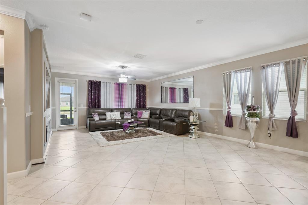 A spacious living room features tile flooring, a large sectional sofa, and floor-to-ceiling window curtains — 9650 IVORY DRIVE, RUSKIN, FL