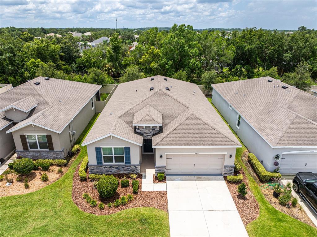 An aerial view shows a single-story house with a tan roof, beige siding, and stone accents — 31420 TANSY BEND, WESLEY CHAPEL, FL