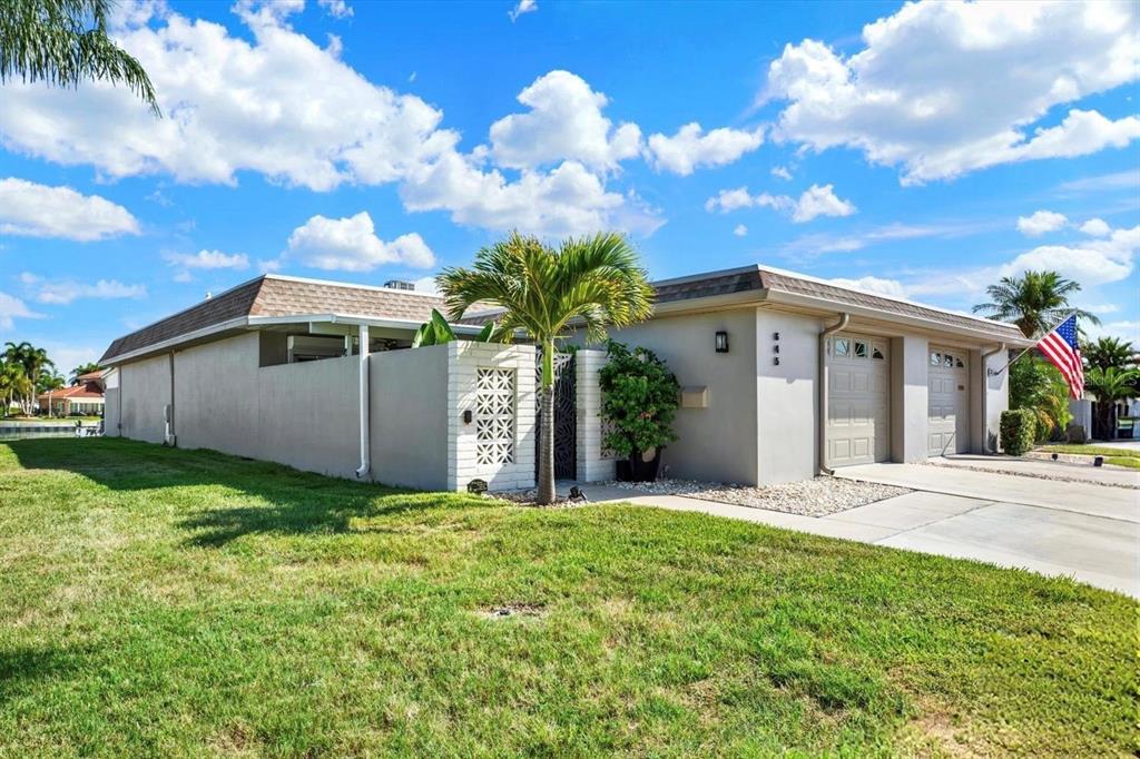 A single-story house with a beige exterior, a two-car garage, and a decorative privacy wall — 645 BOCA CIEGA POINT BOULEVARD N, ST PETERSBURG, FL