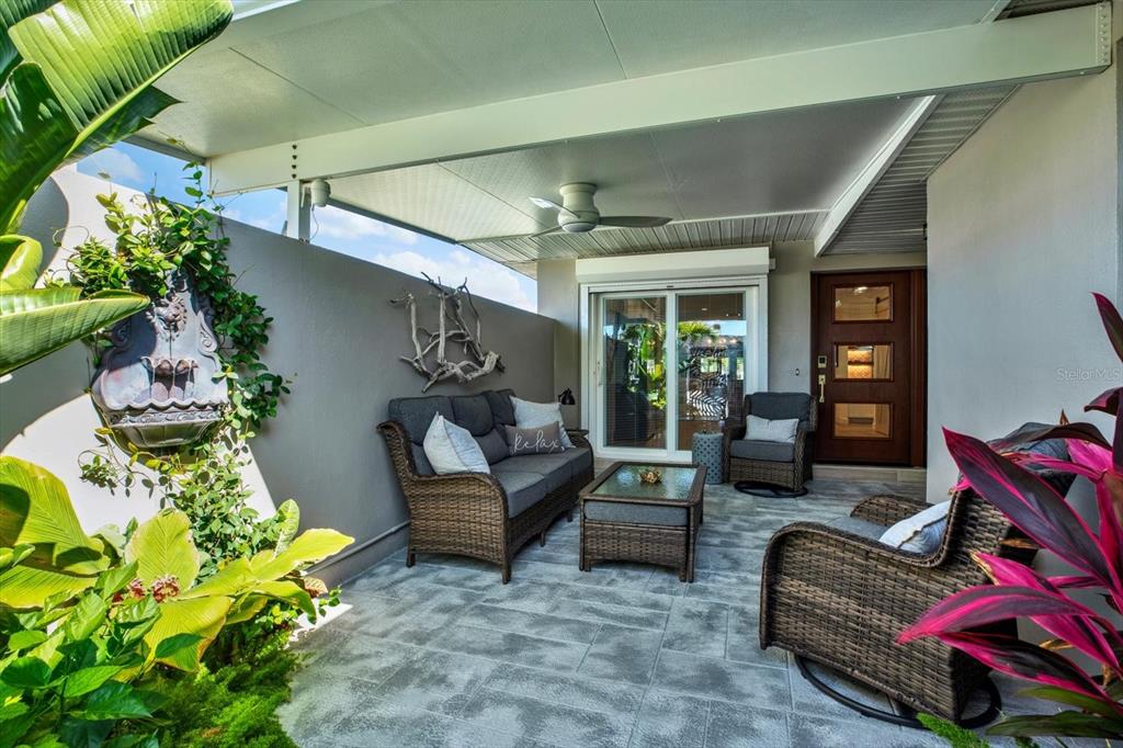 A covered patio features wicker furniture, a wall fountain, and tile flooring — 645 BOCA CIEGA POINT BOULEVARD N, ST PETERSBURG, FL