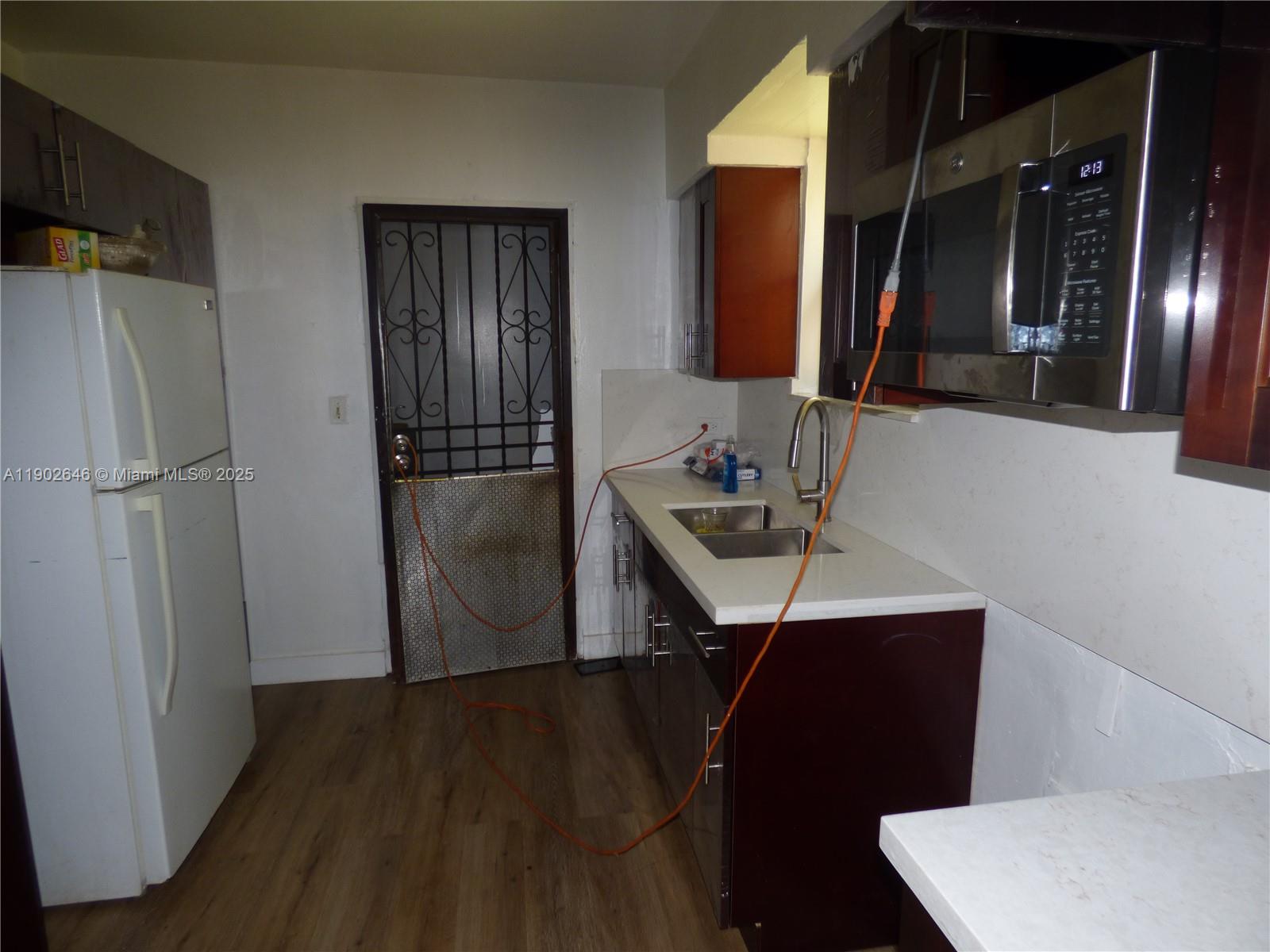 A kitchen features dark wood cabinets, white countertops, a stainless steel microwave, and an orange extension cord — 347 NW 42nd St, Miami FL 33127, MIAMI, FL