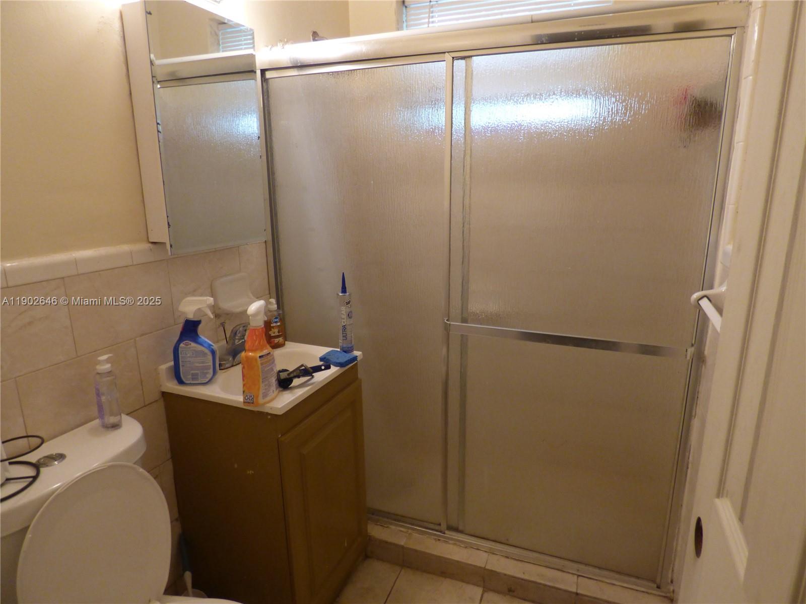 A small bathroom features a pedestal sink, a toilet, and a glass-enclosed shower stall — 347 NW 42nd St, Miami FL 33127, MIAMI, FL