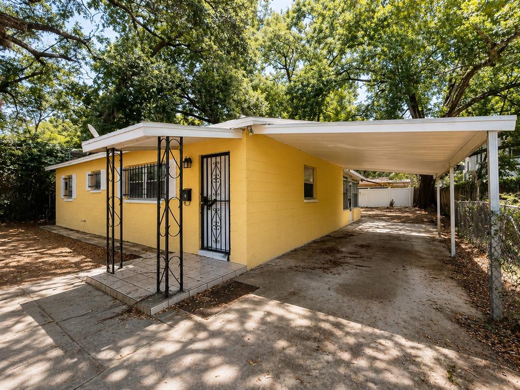 A yellow, single-story house with a concrete carport and a small tiled front porch — 1003 E 22ND AVENUE, TAMPA, FL