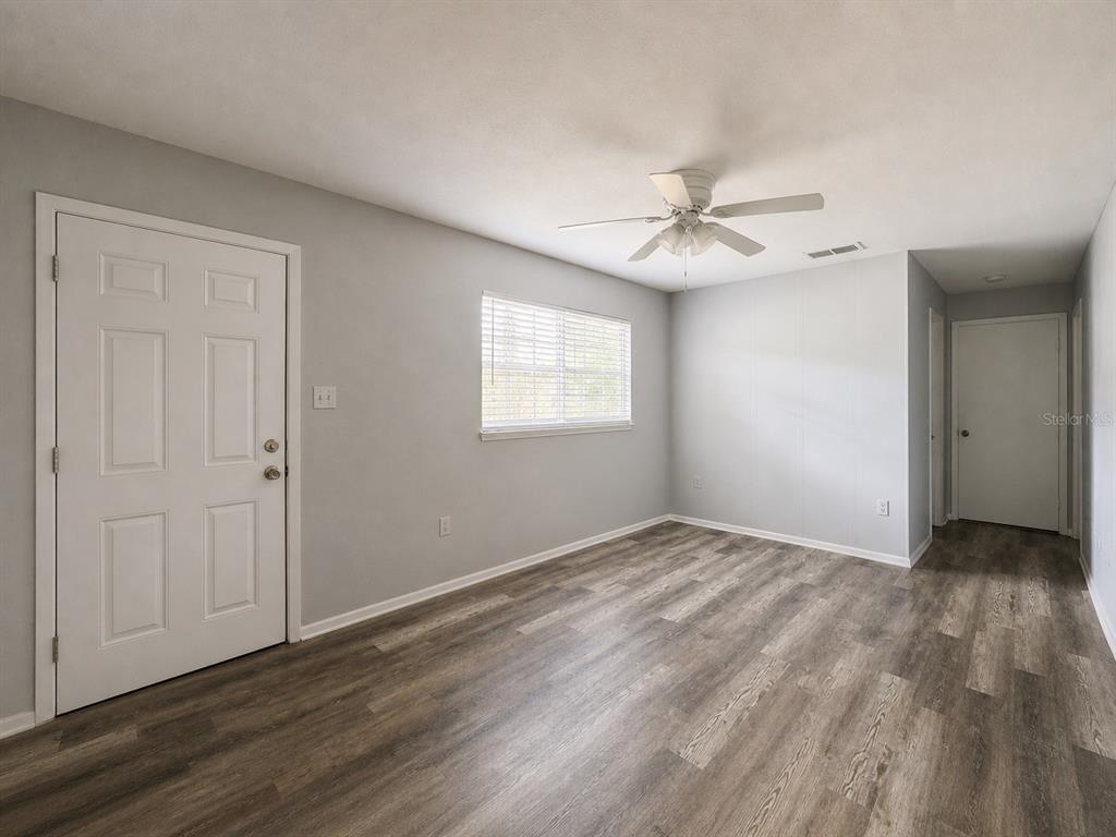 A room with light gray walls, wood-look flooring, a ceiling fan, and two white doors — 1003 E 22ND AVENUE, TAMPA, FL