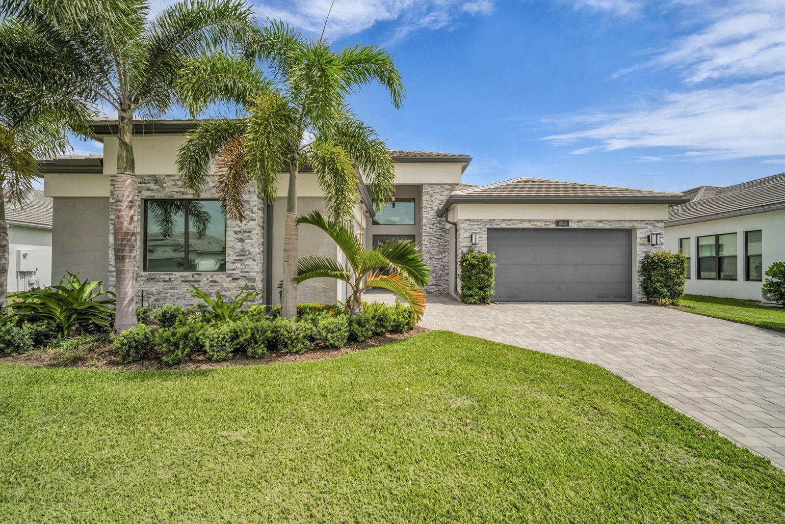 A modern single-story house features a stone facade, a gray garage, and palm trees — 10925 Glen Orchard Lane, Boynton Beach FL 33473, BOYNTON BEACH, FL