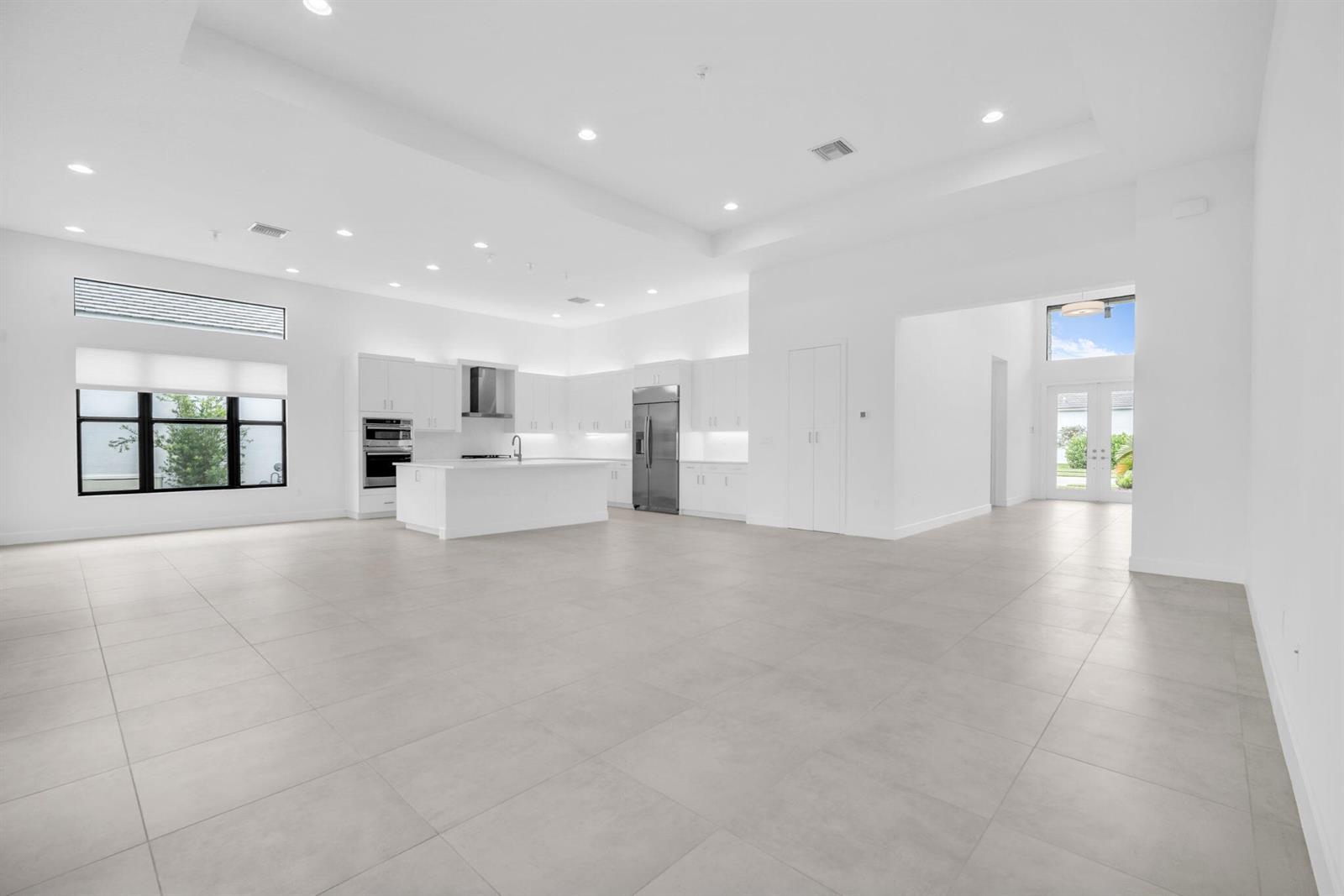 A spacious, minimalist white kitchen and living area with large tile floors and recessed lighting — 10925 Glen Orchard Lane, Boynton Beach FL 33473, BOYNTON BEACH, FL